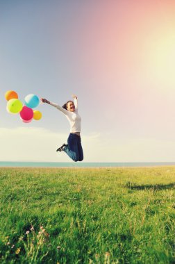 Yeşil otlak renkli balonlar ile atlama genç Asyalı kadın