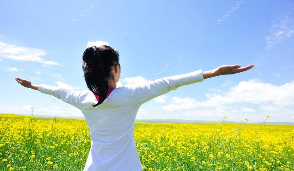 Cheering woman open arms at cole flower field