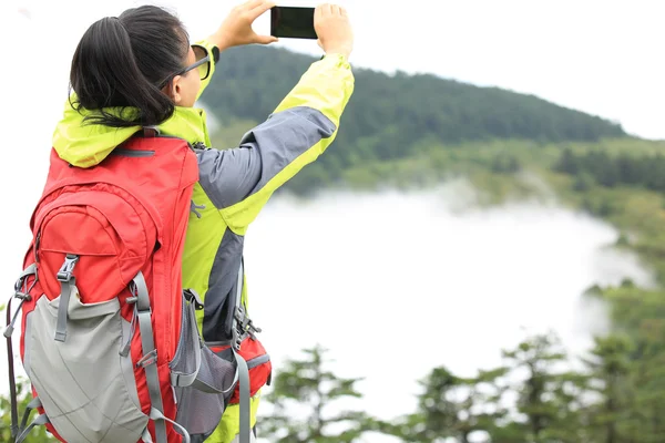 Woman hiker taking photo with cell phone at peak of emei mountain ,china — Stock Photo, Image