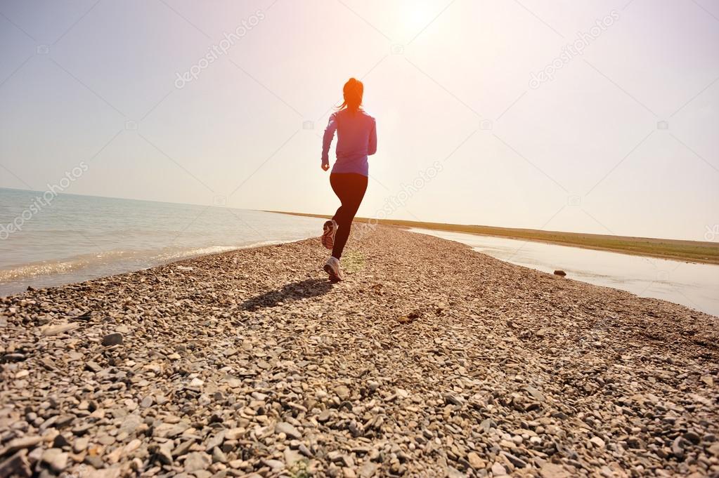 Runner athlete running on stone beach of qinghai lake.