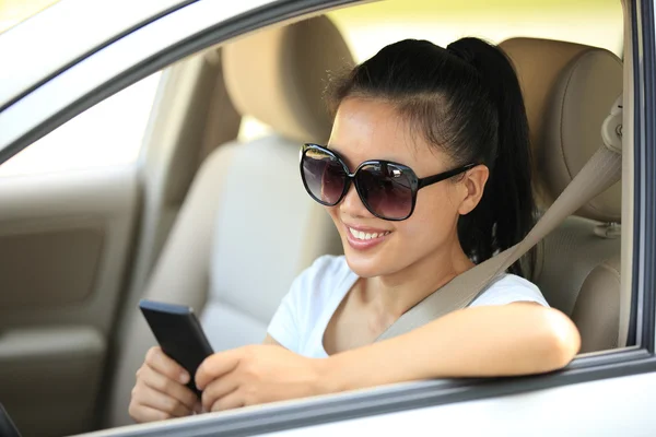 Женщина-водитель использует свой мобильный телефон в машине — стоковое фото