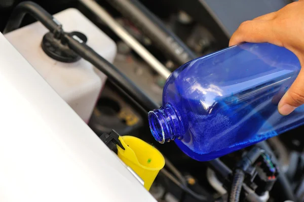 Manos añadiendo auto limpiador de vidrio para el coche — Foto de Stock