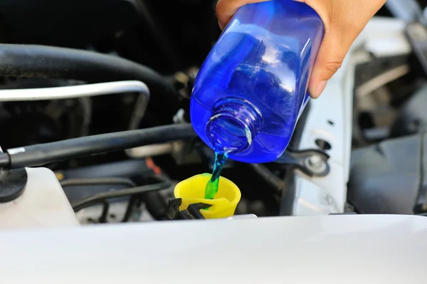 Hands adding auto glass cleaner for car — Stock Photo, Image