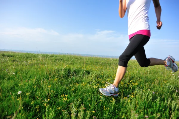 Runner athlete legs running on grass seaside. — Stock Photo, Image