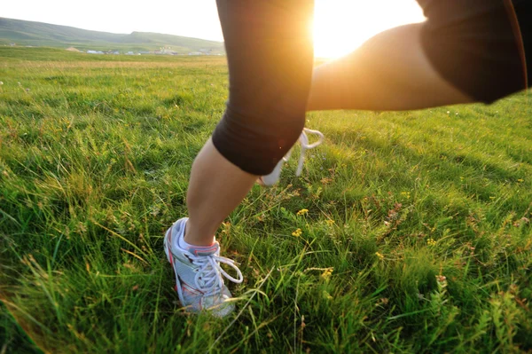 Runner atlet bacaklar çim sahil üzerinde çalışan. — Stok fotoğraf