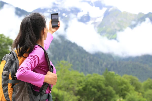 Mujer excursionista tomando fotos con teléfono celular en el pico de la montaña en el Tíbet, China —  Fotos de Stock