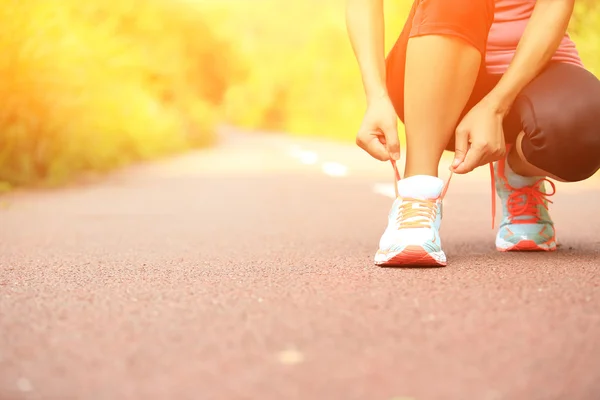 Young woman runner tying shoelaces — Stock Photo, Image