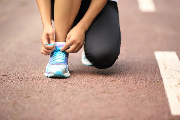 Giovane donna corridore allacciatura lacci delle scarpe — Foto Stock