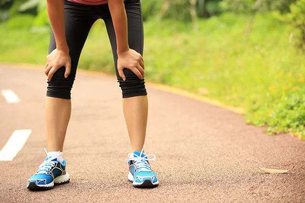 Moe vrouw loper een rust na het uitvoeren van hard in het platteland weg te nemen. — Stockfoto