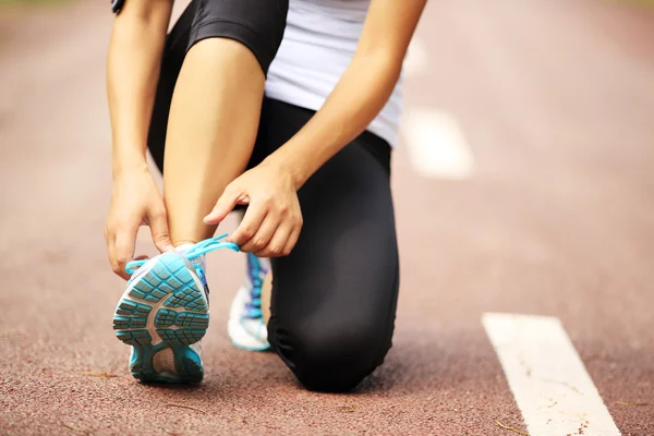 Young woman runner tying shoelaces — Stock Photo, Image