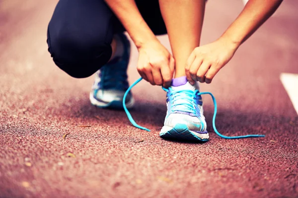 Young woman runner tying shoelaces — Stock Photo, Image