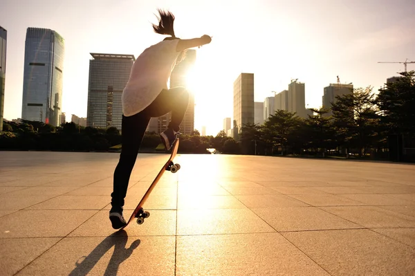 Žena skateboarder skateboarding při východu slunce města — Stock fotografie