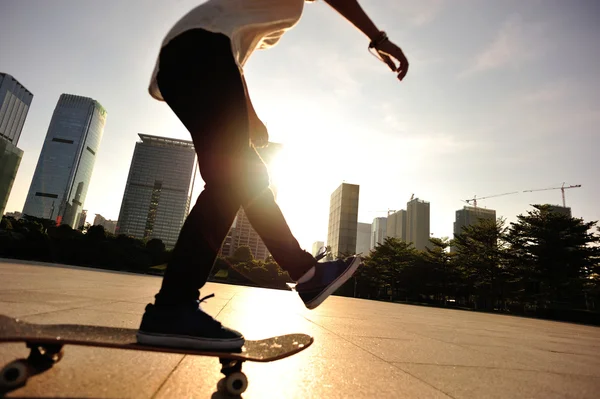 Vrouw skateboarder skateboarden bij zonsopgang stad — Stockfoto