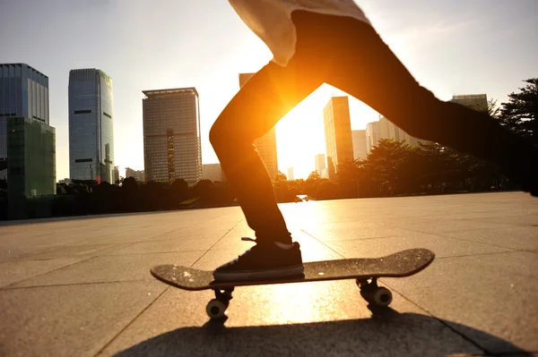 Žena skateboarder skateboarding při východu slunce města — Stock fotografie