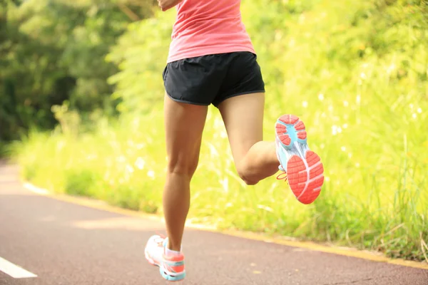 Joven fitness piernas de mujer corriendo en el camino del bosque — Foto de Stock