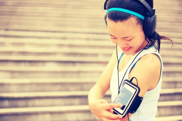 Corredor atleta escuchando música en los auriculares de teléfono inteligente reproductor de mp3 brazalete de teléfono inteligente . —  Fotos de Stock