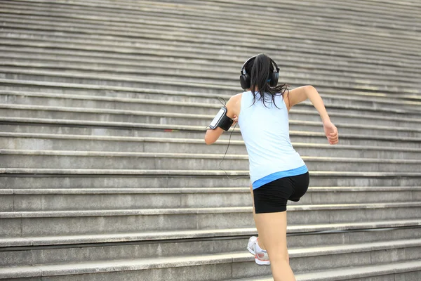 Atleta corridore che corre sulle scale. ascolto di musica in cuffie da smartphone lettore mp3 bracciale smartphone . — Foto Stock