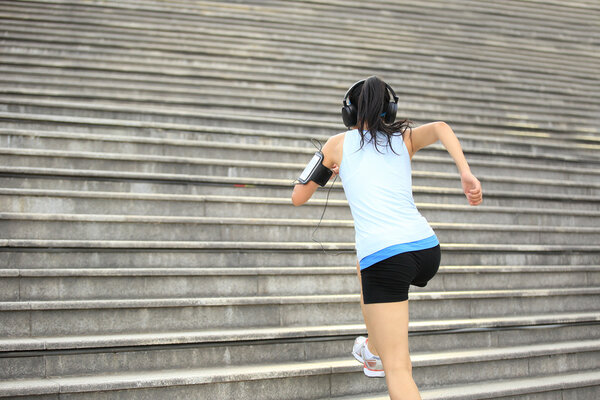 Runner athlete running on stairs. listening to music in headphones from smart phone mp3 player smart phone armband.