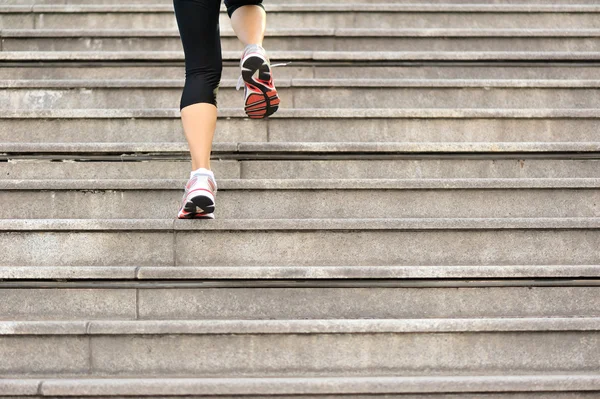 Sports woman legs running up on stone stairs — Stock Photo, Image