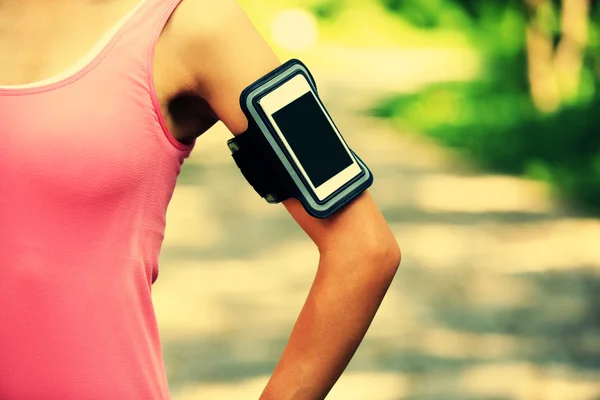 Löpare idrottsman lyssna på musik från smart telefon mp3 spelare smart telefon armband. — Stockfoto