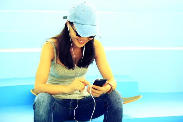 Femme skateboarder assis sur les escaliers skatepark écouter de la musique — Photo