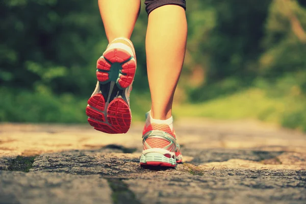 Joven fitness piernas de mujer corriendo en el camino del bosque — Foto de Stock