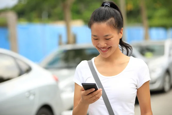 女人用她的手机走在停车场 — 图库照片