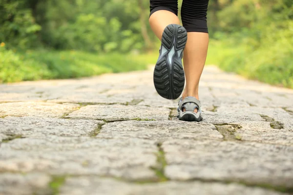 Jeune femme fitness jambes en cours d'exécution au sentier forestier — Photo