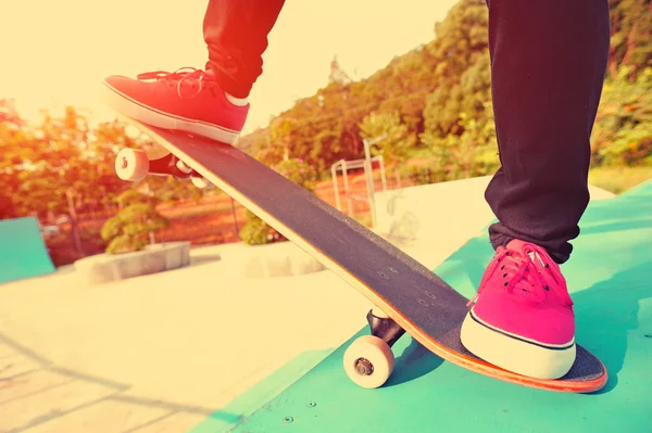 Skateboarden benen van de vrouw bij zonsopgang skatepark — Stockfoto