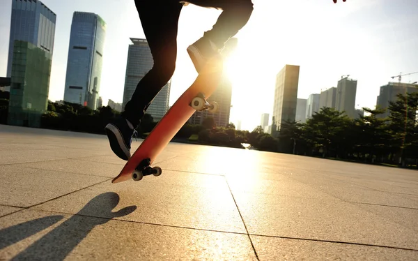 Femme skateboard skateboard au lever du soleil ville — Photo