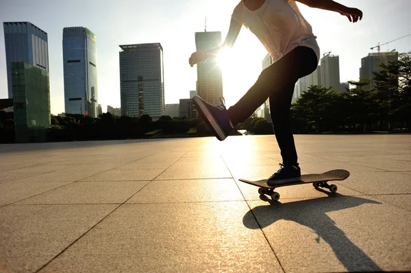 Woman skateboarder skateboarding at sunrise city — Stock Photo, Image