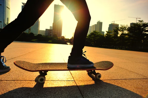 Žena skateboarder skateboarding při východu slunce města — Stock fotografie