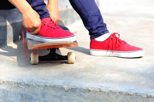 Young woman skateboarder tying shoelace — Stock Photo, Image