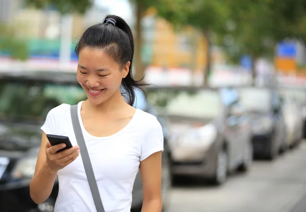 Frau benutzt ihr Handy beim Gehen auf Parkplatz — Stockfoto