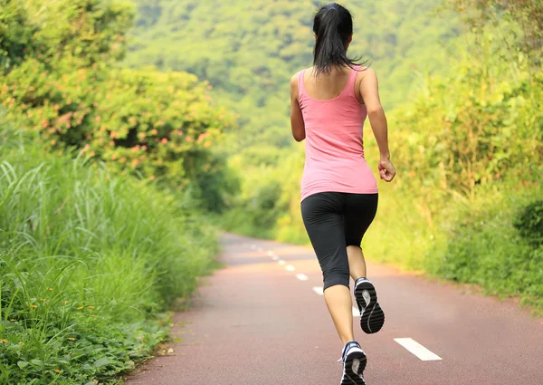 Молодая фитнес-женщина бегает по лесной тропе — стоковое фото