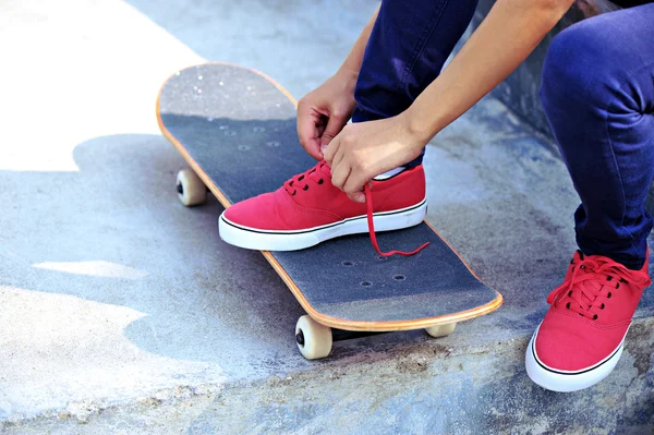 Jeune femme skateboarder attacher lacet — Photo