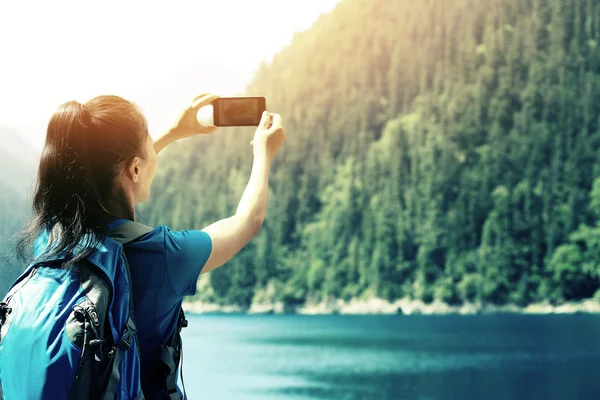 Turista mujer tomando fotos con teléfono inteligente en el parque nacional de jiuzhaigou, China — Foto de Stock