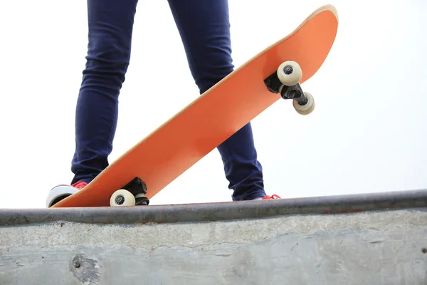 Jeune femme jambes skateboard à la rampe skatepark — Photo