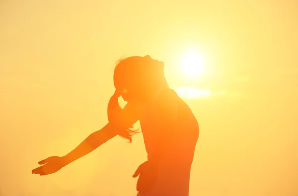 Mujer brazos abiertos bajo el amanecer en el mar —  Fotos de Stock