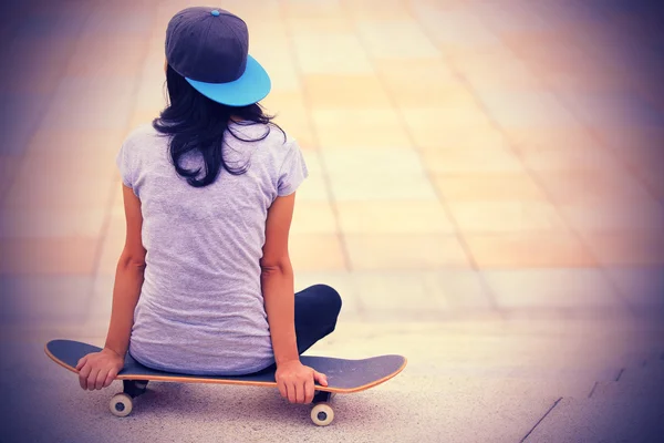 Скейтбордист сидит на скейтборде — стоковое фото