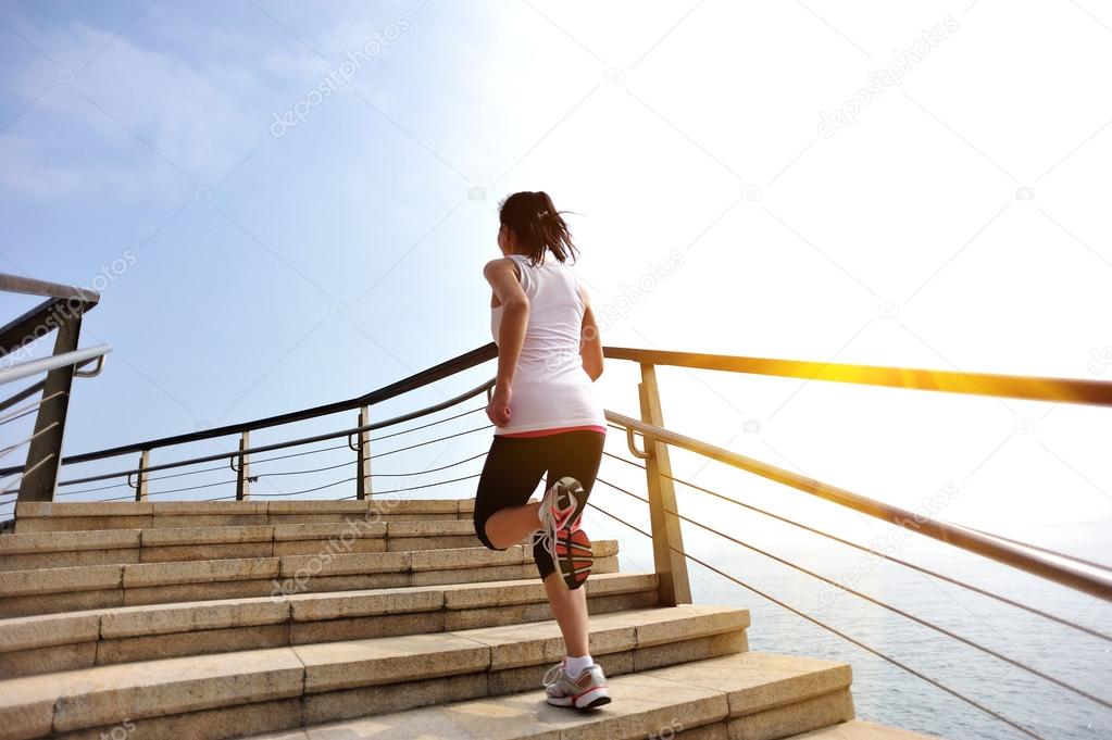 Sports woman running on stone stairs seaside