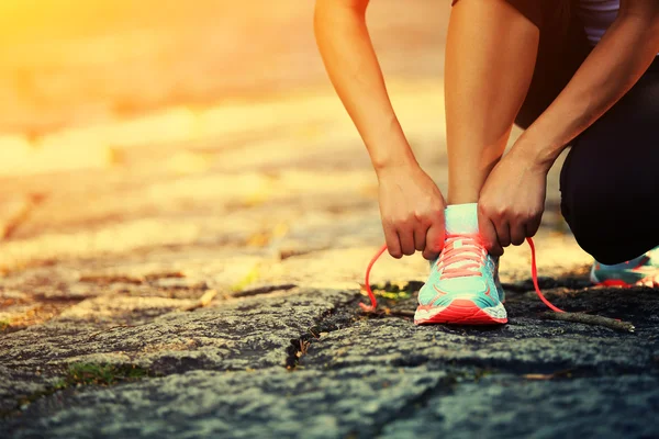 Young woman runner tying shoelaces — Stock Photo, Image