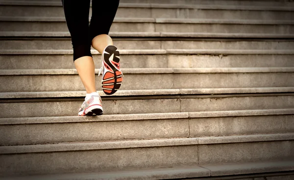 Jambes de femme courant sur des escaliers en pierre — Photo