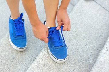 Kadın kaykaycı ayakkabı bağı bağlıyor.