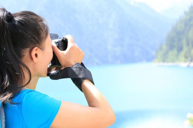 Kadın fotoğrafçı dijital kamerayla fotoğraf çekiyor.