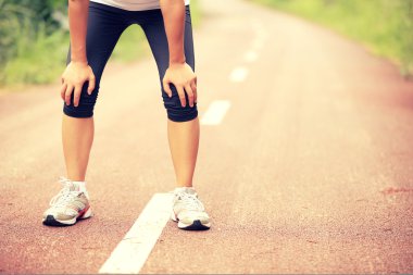 Yorgun bayan koşucu kırsal yolda koştuktan sonra dinleniyor. Country Road 'da maraton koşusundan sonra terli sporcu.