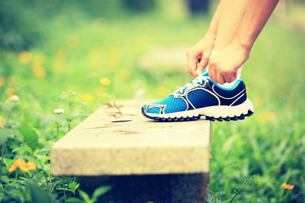 Young woman runner tying shoelaces