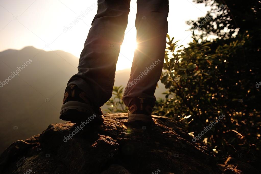Woman hiker stand on mountain peak rock