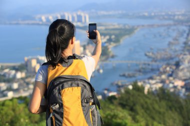 genç kadın hiker kullanmak akıllı telefon dağın zirvesinde kendini fotoğrafı çekmek