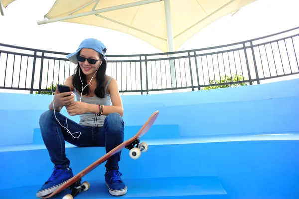 Femme skateboarder écouter de la musique de téléphone intelligent lecteur mp3 — Photo